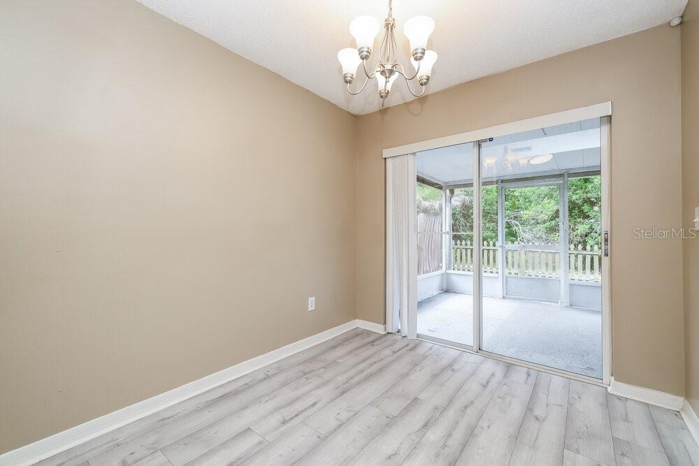 A dining area with light wood-look flooring, a chandelier, and sliding doors to a screened porch — 6719 SUMMER COVE DRIVE, RIVERVIEW, FL