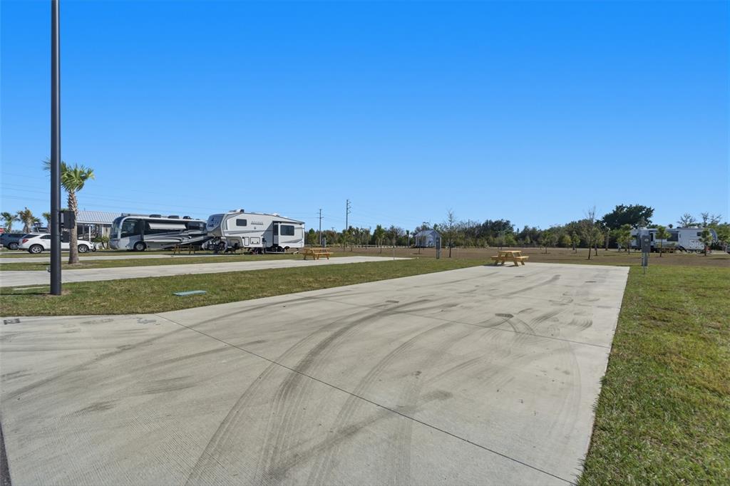 A concrete RV pad with tire marks sits in a grassy lot with parked campers — 232 RIVERCLUB COURT, PUNTA GORDA, FL