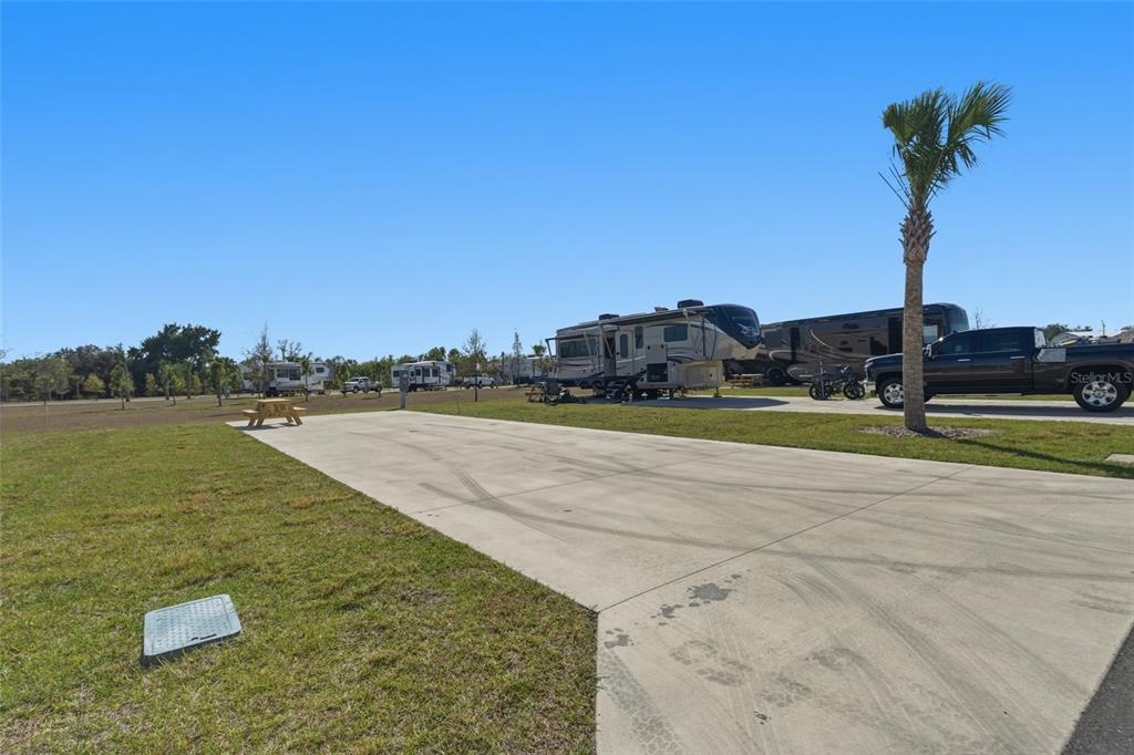 A concrete RV pad sits in an open grassy lot with several parked recreational vehicles — 232 RIVERCLUB COURT, PUNTA GORDA, FL
