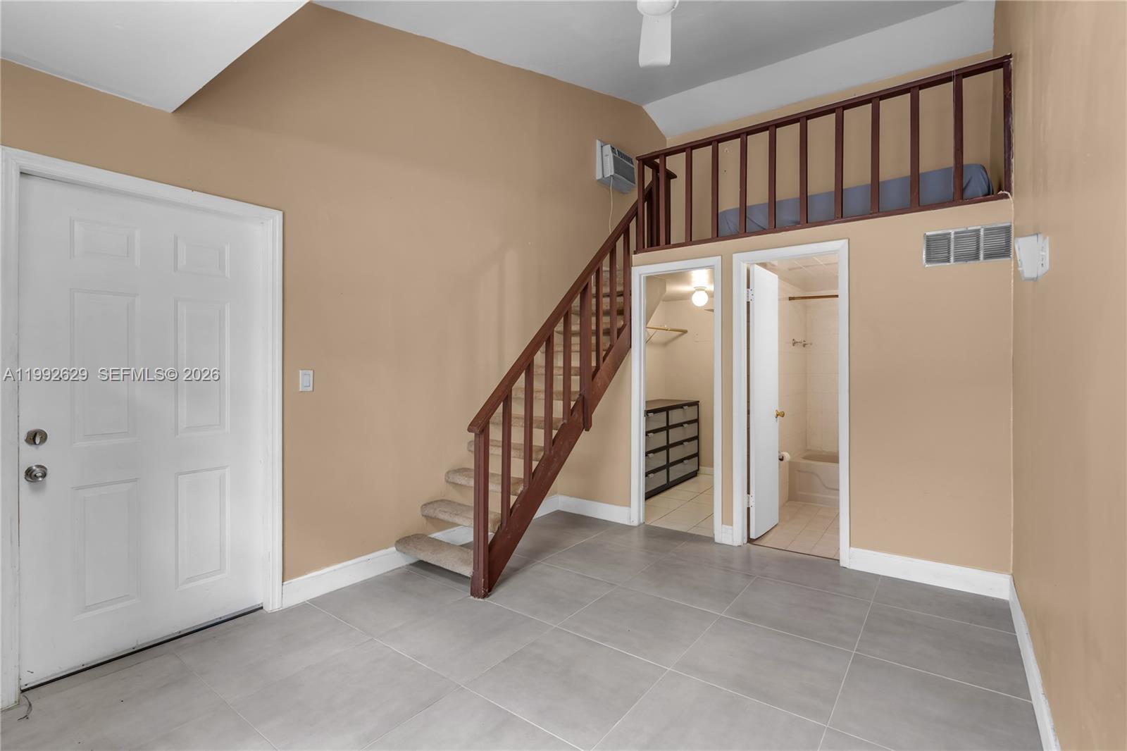 A room features a loft area with a wooden railing, stairs, and two adjacent doorways — 2145 SW 26 ST, Miami FL 33133, MIAMI, FL