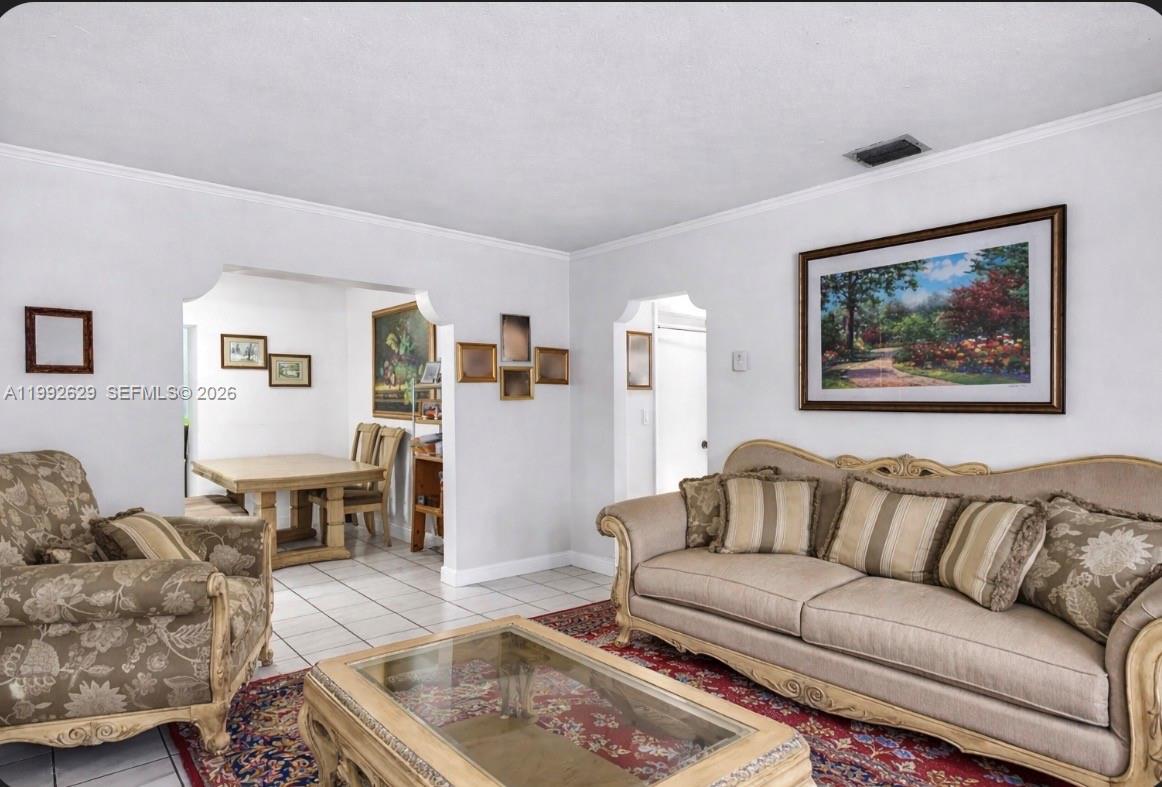 A living room with a beige sofa, patterned armchair, glass coffee table, and tiled floors — 2145 SW 26 ST, Miami FL 33133, MIAMI, FL