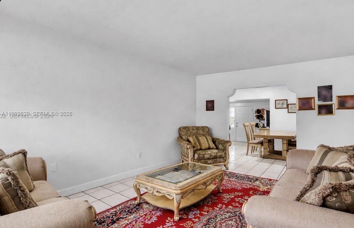 A living room with tile floors, a red patterned rug, and a dining area beyond — 2145 SW 26 ST, Miami FL 33133, MIAMI, FL