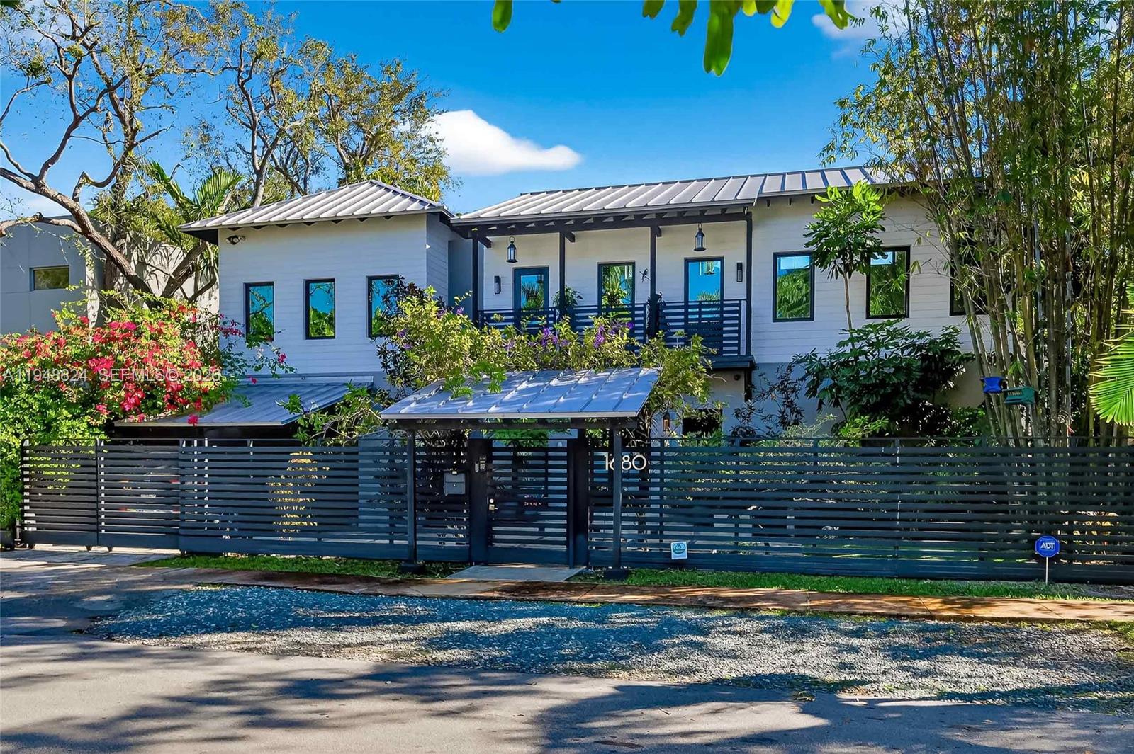 A two-story house with a metal roof, white siding, and a dark horizontal slat fence — 1680 Onaway Dr, Coconut Grove FL 33133, COCONUT GROVE, FL
