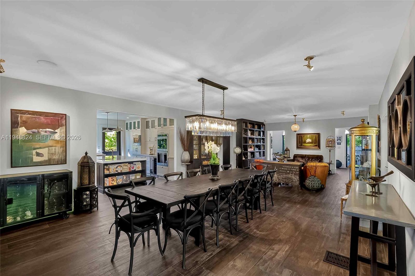 A dining room features a long dark wood table, black chairs, and a crystal chandelier — 1680 Onaway Dr, Coconut Grove FL 33133, COCONUT GROVE, FL