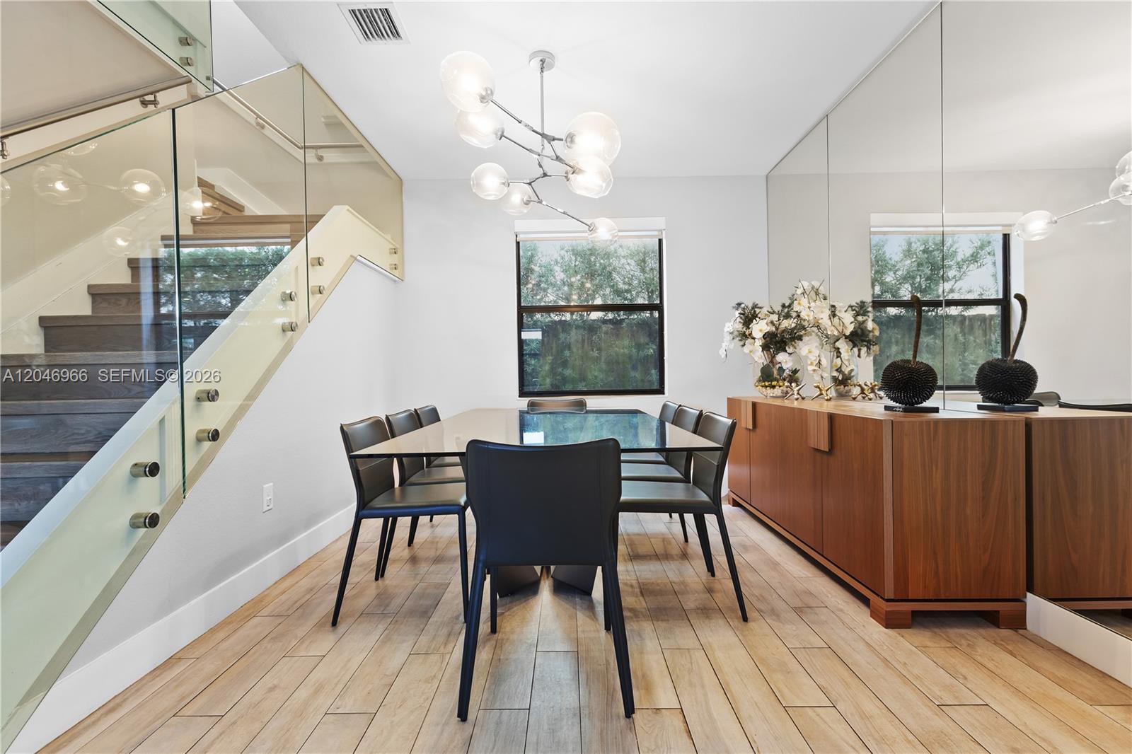 A dining room features a glass table, black chairs, a wooden sideboard, and a staircase — 8774 NW 103rd Ave, Doral FL 33178, DORAL, FL