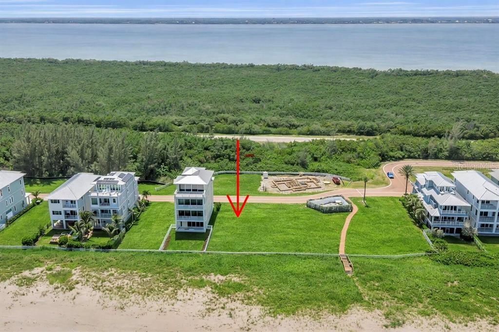 An aerial view shows a vacant beachfront lot situated between two multi-story residential buildings — 5104 WATERSONG WAY, FORT PIERCE, FL