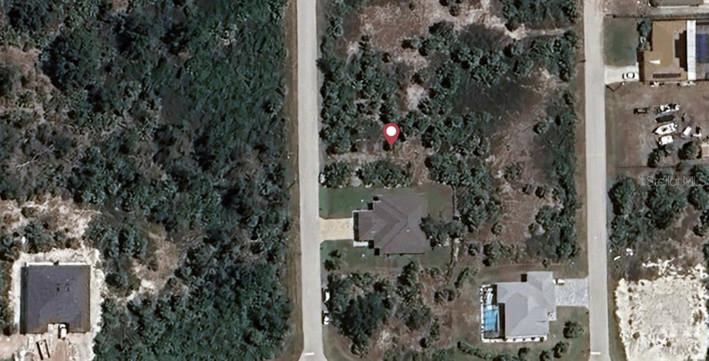 This aerial view shows a vacant lot marked with a pin next to existing houses — 10476 PORT EVERGLADES STREET, PORT CHARLOTTE, FL