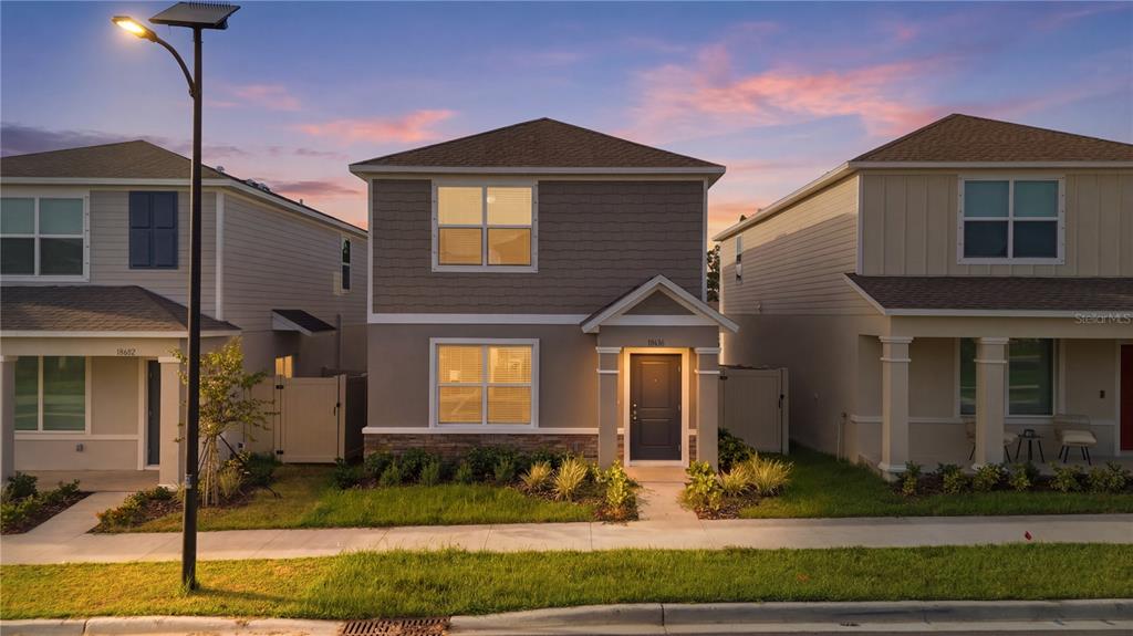 A two-story suburban house with a gray exterior, stone accents, and a front porch — 10636 SAGE CANYON DRIVE, RIVERVIEW, FL
