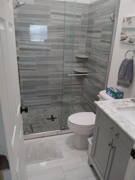 A bathroom features a glass-enclosed walk-in shower with gray tile and a marble-topped vanity — 913 WATERSIDE LANE UNIT 913, BRADENTON, FL