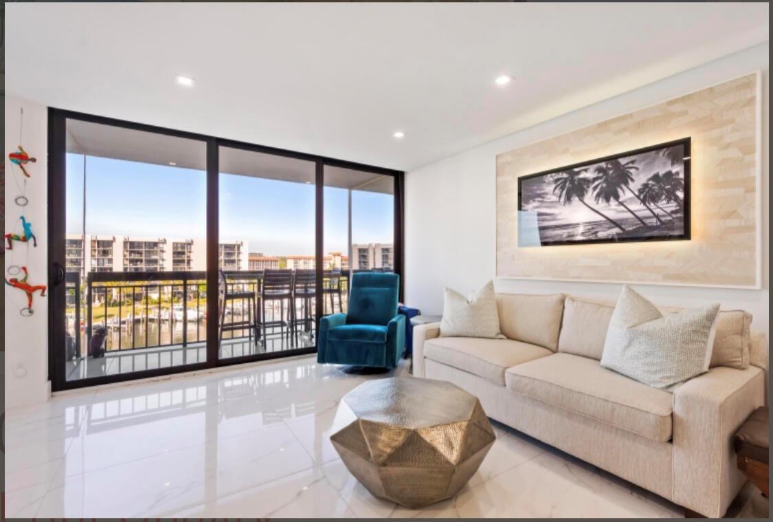A living room with a beige sofa, teal armchair, metallic coffee table, and balcony view — 2687 N Ocean Boulevard # G506, Boca Raton FL 33431, BOCA RATON, FL