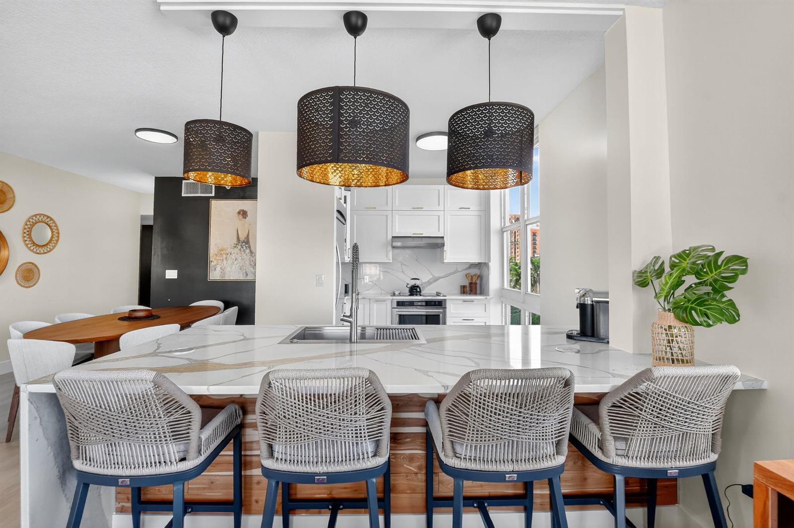 A kitchen features a marble-topped island with four woven stools and three hanging pendant lights — 550 Okeechobee Boulevard # 502, West Palm Beach FL 33401, WEST PALM BEACH, FL