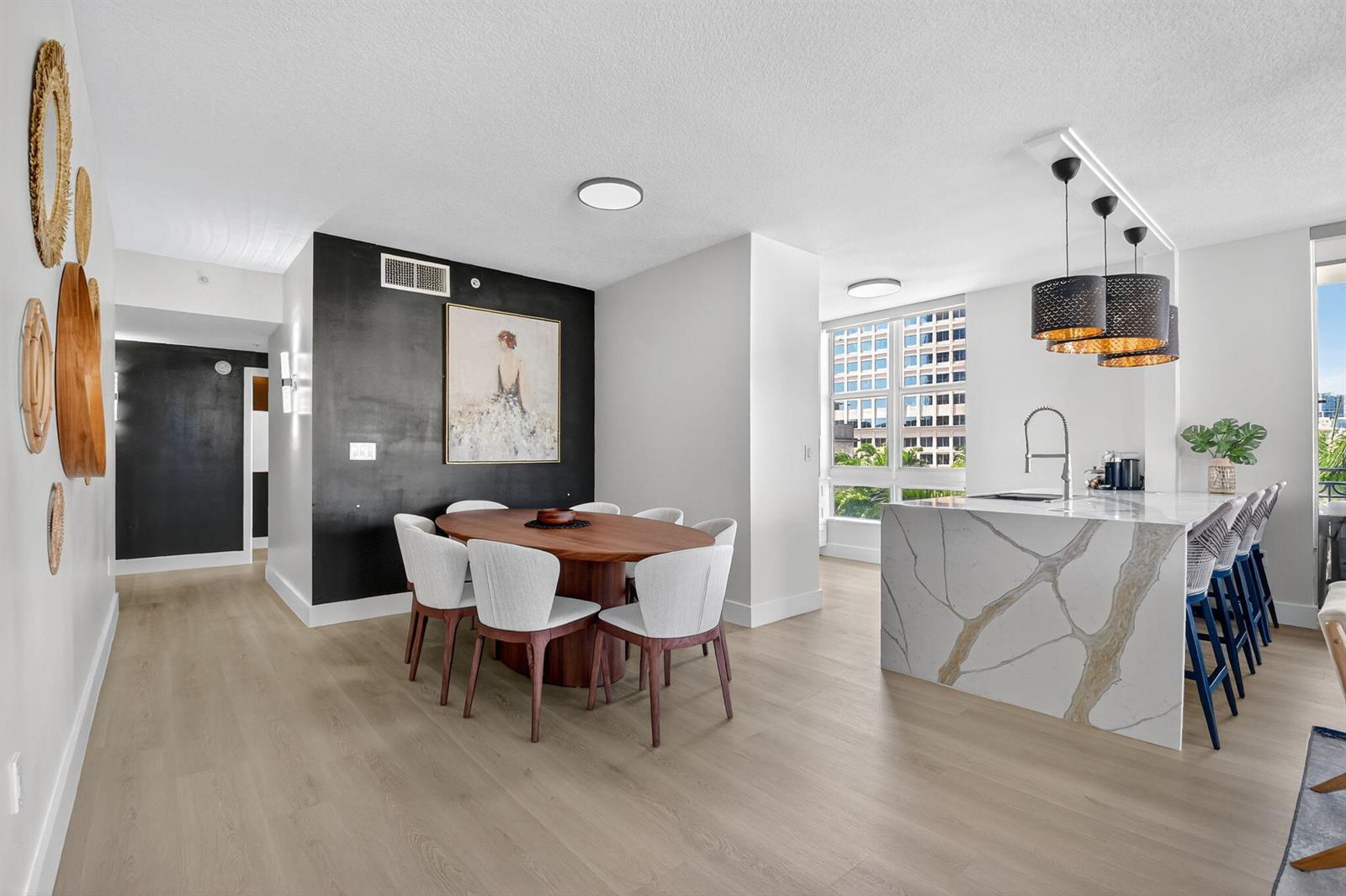 A dining area with a wooden table and white chairs sits beside a marble-topped kitchen island — 550 Okeechobee Boulevard # 502, West Palm Beach FL 33401, WEST PALM BEACH, FL