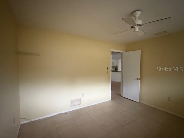 An empty room with light yellow walls, tile flooring, a ceiling fan, and an open door — 4051 BENT TREE BOULEVARD, SARASOTA, FL