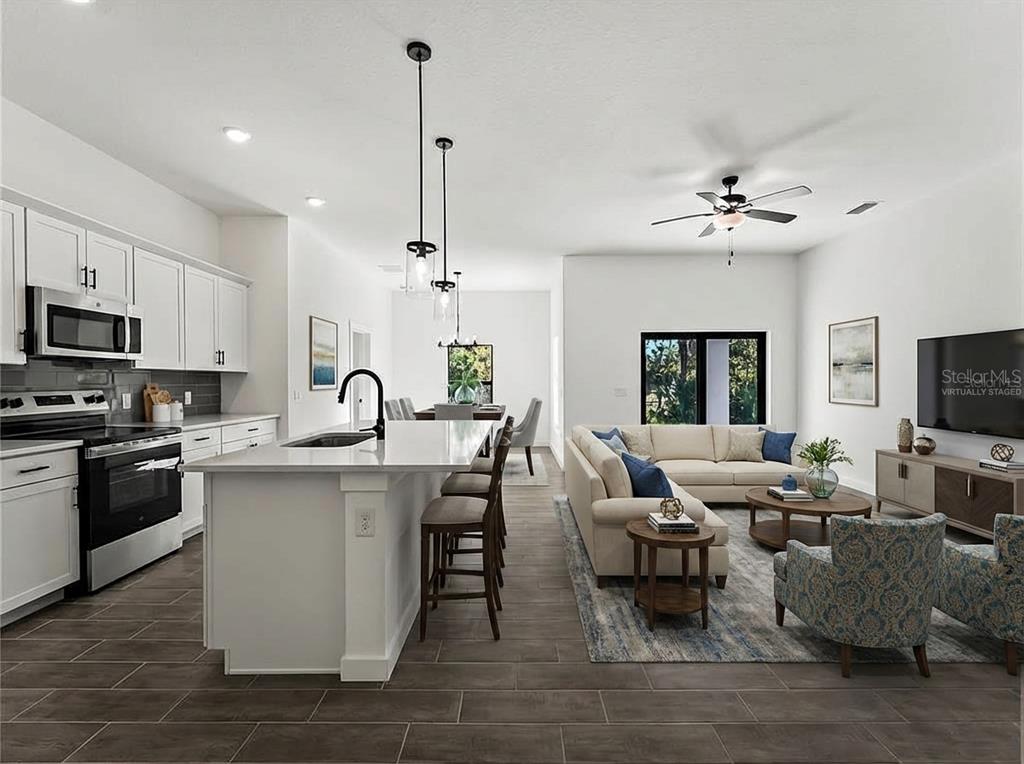 An open-concept kitchen and living area features white cabinetry, a central island, and tile flooring — 3085 STOCKTON AVENUE, NORTH PORT, FL