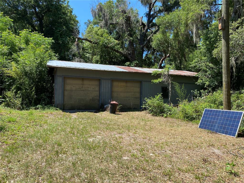 A detached two-car garage with a metal roof sits in a wooded, grassy lot — 2424 NE 170TH STREET, CITRA, FL