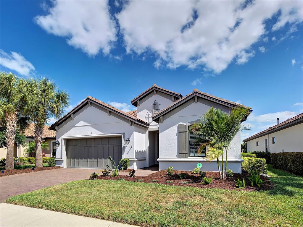 A single-story suburban house with a two-car garage, palm trees, and a landscaped front yard — 5616 SCARLOTTI STREET, NOKOMIS, FL