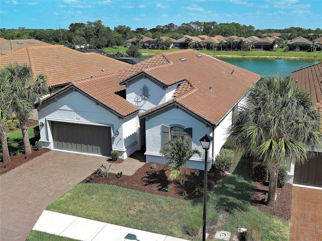 An aerial view of a single-story house with a tile roof, garage, and palm trees — 5616 SCARLOTTI STREET, NOKOMIS, FL