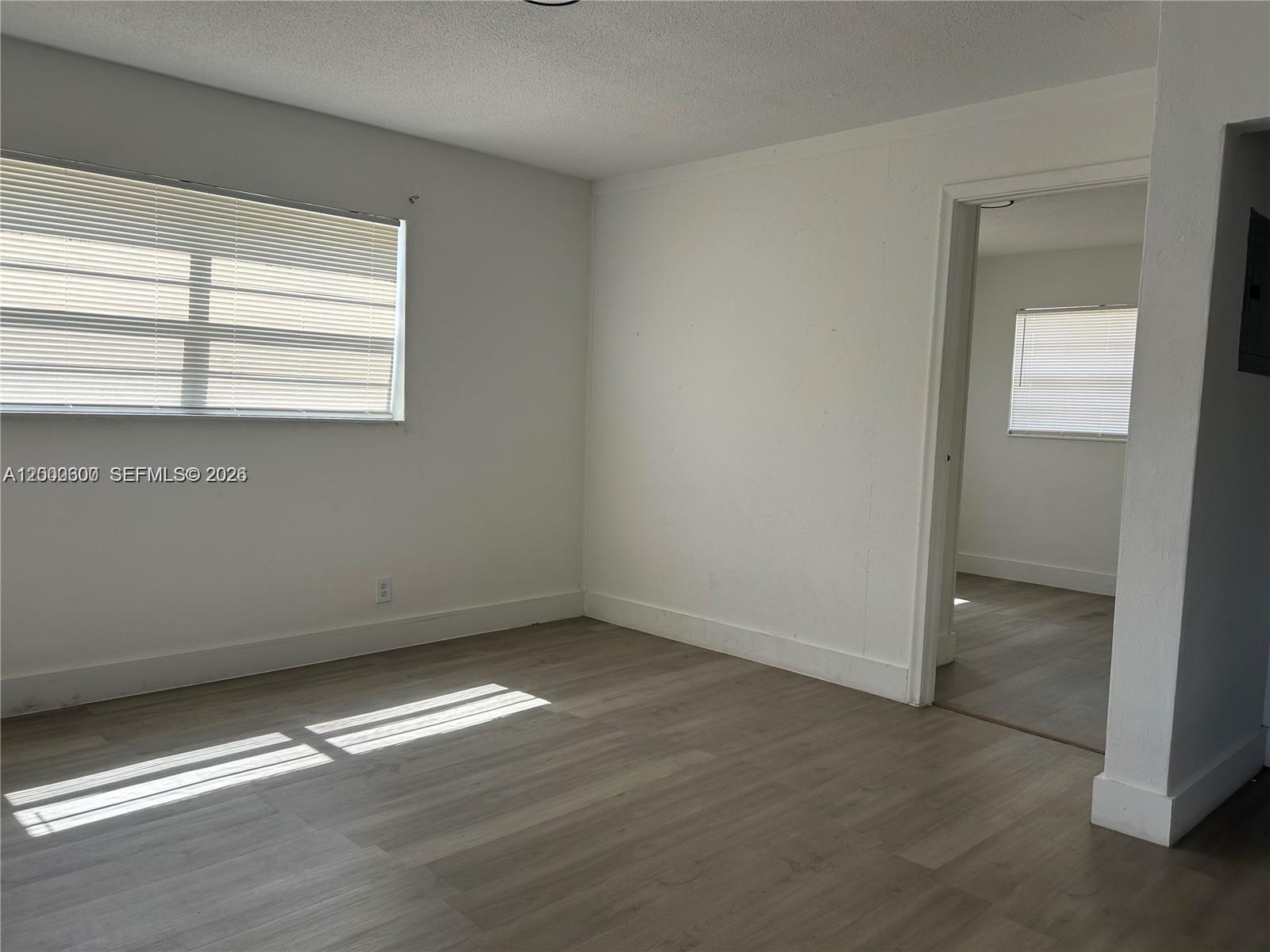 An empty room with light wood-look flooring, white walls, and a doorway to another room — 904 SW 10th St, Hallandale Beach FL 33009, HALLANDALE BEACH, FL