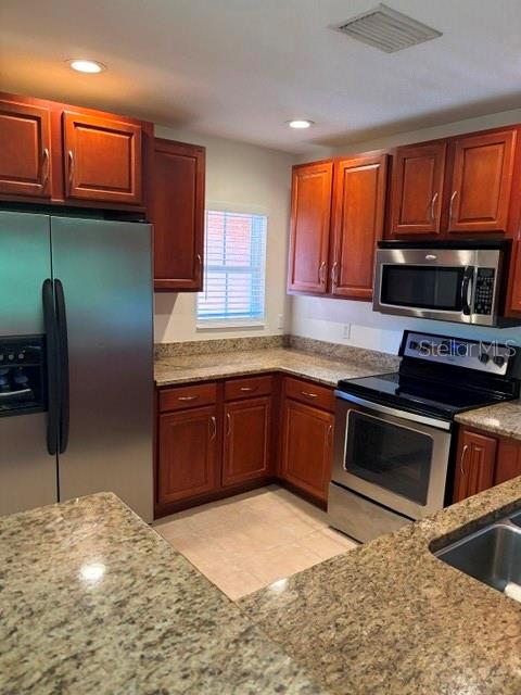 A kitchen features wood cabinets, granite countertops, and stainless steel appliances — 8858 WHITE SAGE LOOP, LAKEWOOD RANCH, FL