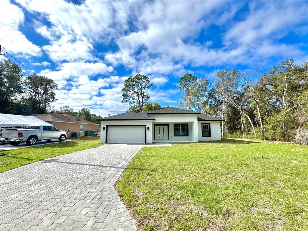 A modern white single-story house with a black roof and a paved driveway — 9082 N CORTLANDT DRIVE, CITRUS SPRINGS, FL
