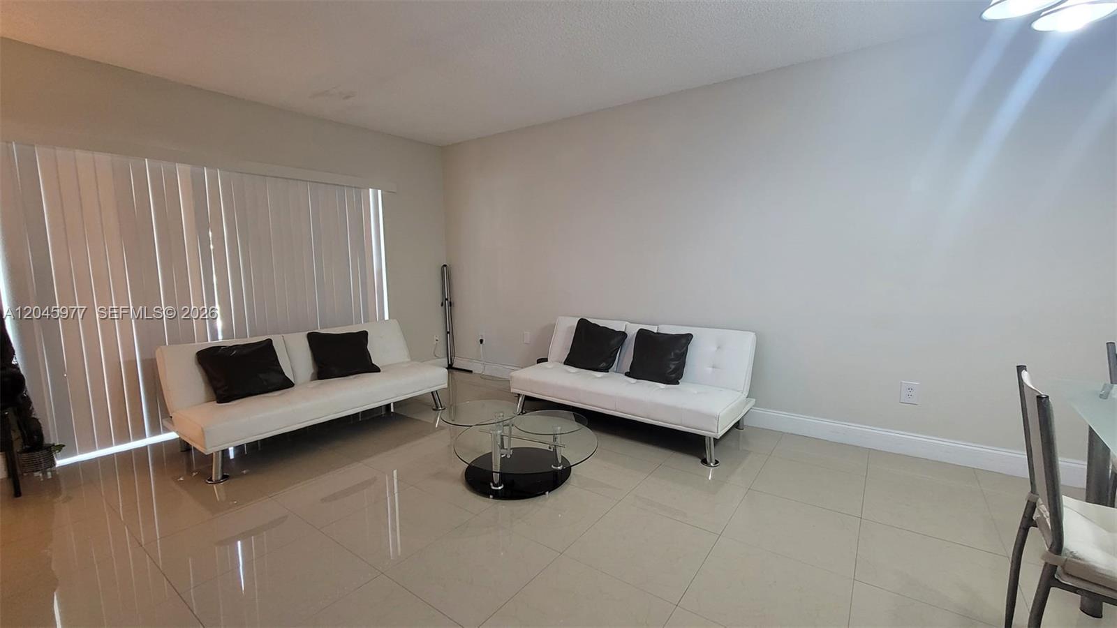 A living room features two white futons, a glass coffee table, and light tile flooring — 7705 Camino Real # 215, Miami FL 33143, MIAMI, FL