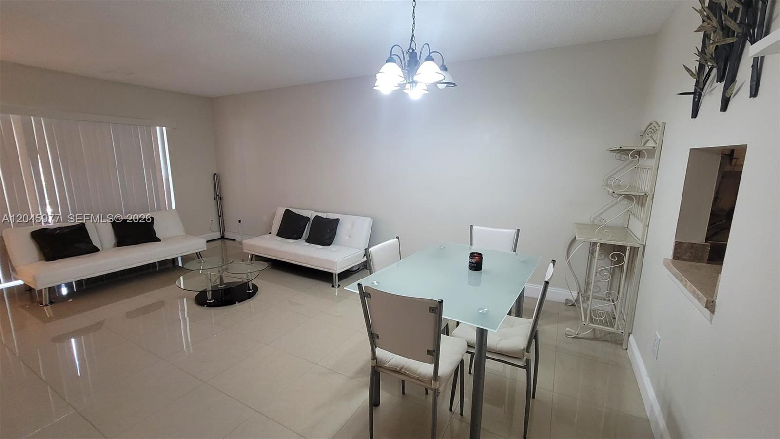 This living and dining area features white tile floors, two white futons, and a glass-topped table — 7705 Camino Real # 215, Miami FL 33143, MIAMI, FL