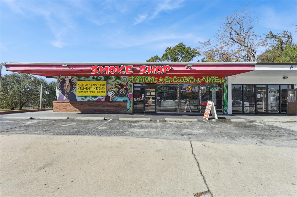 The exterior of a commercial smoke shop building features a red awning and mural artwork — 107 S 14TH STREET, LEESBURG, FL
