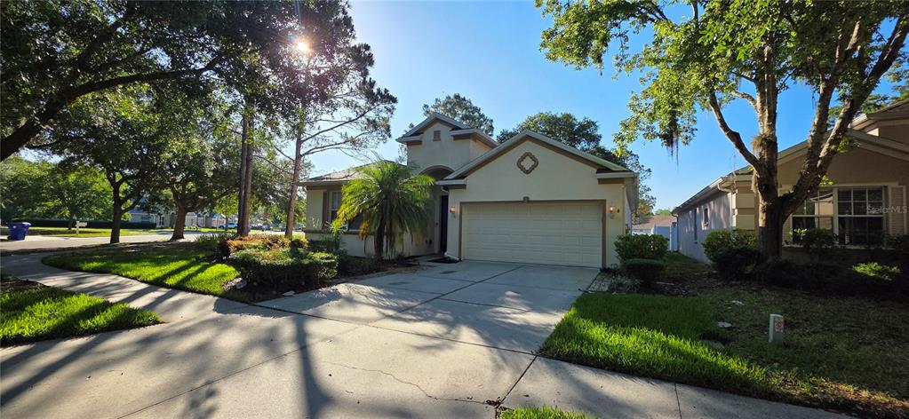 A single-story suburban house with a beige stucco exterior and a two-car garage — 10906 TREE CACTUS LOOP, LAND O LAKES, FL