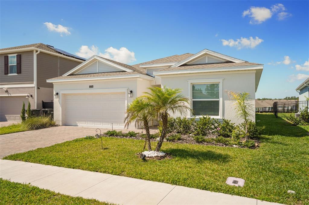 A single-story house with a white stucco exterior, a two-car garage, and a palm tree — 5256 DAGENHAM DRIVE, DAVENPORT, FL