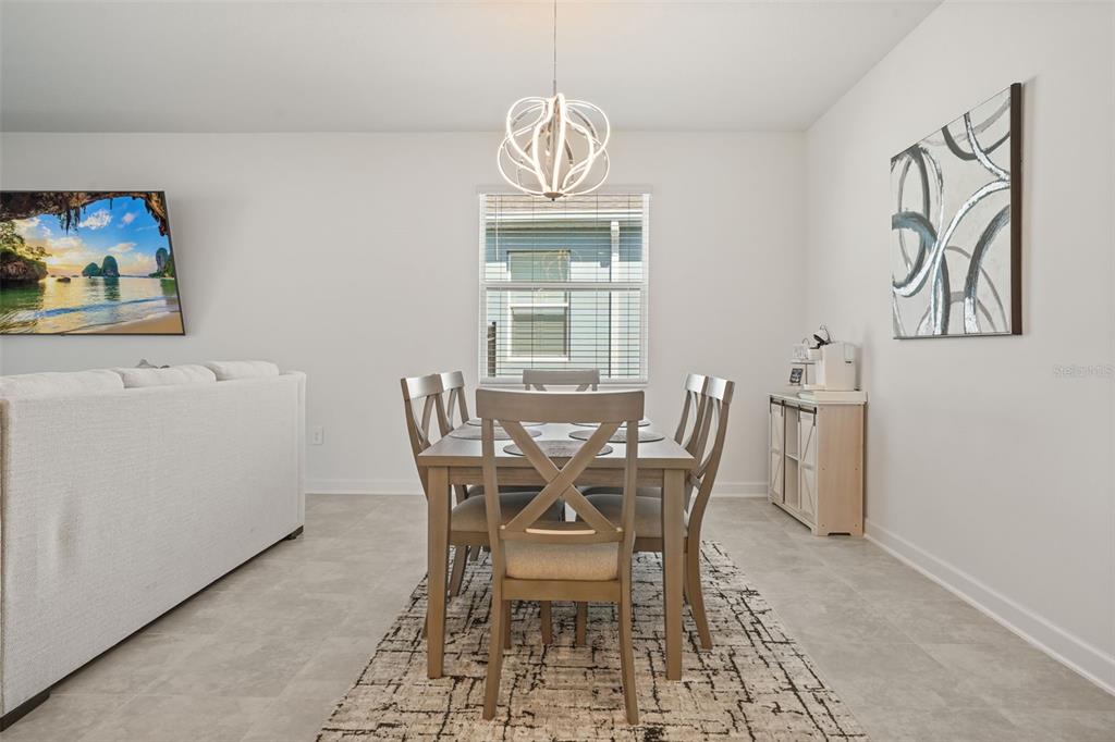 A dining room features a wooden table, chairs, a pendant light, and a patterned rug — 5256 DAGENHAM DRIVE, DAVENPORT, FL