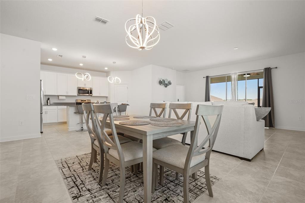 A dining area with a wooden table and chairs sits in front of an open kitchen — 5256 DAGENHAM DRIVE, DAVENPORT, FL