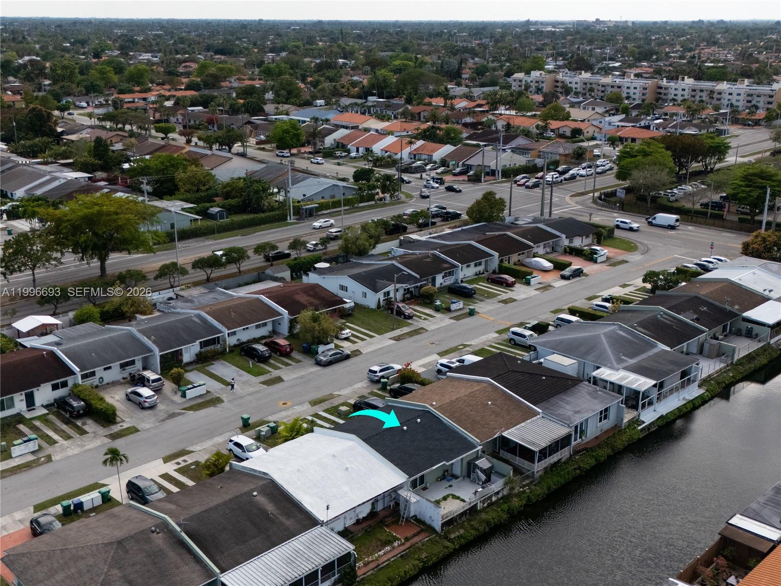An aerial view shows a residential neighborhood with a canal-front house highlighted by an arrow — 10017 SW 23rd Ter, Miami FL 33165, MIAMI, FL
