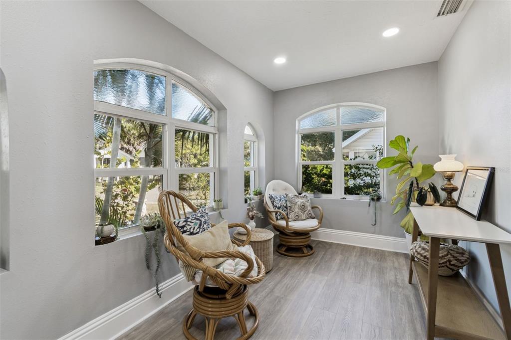 A sunroom with light gray walls, wood-look flooring, two rattan chairs, and large arched windows — 1120 17TH AVENUE N, ST PETERSBURG, FL