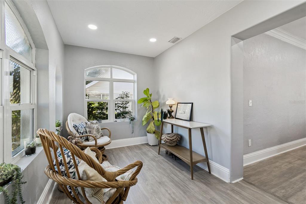 A sunroom features light gray walls, wood-look flooring, arched windows, and two rattan swivel chairs — 1120 17TH AVENUE N, ST PETERSBURG, FL