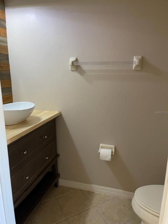A small bathroom features a vessel sink on a wooden vanity and a toilet — 2950 WILLOWLEAF LANE, WESLEY CHAPEL, FL
