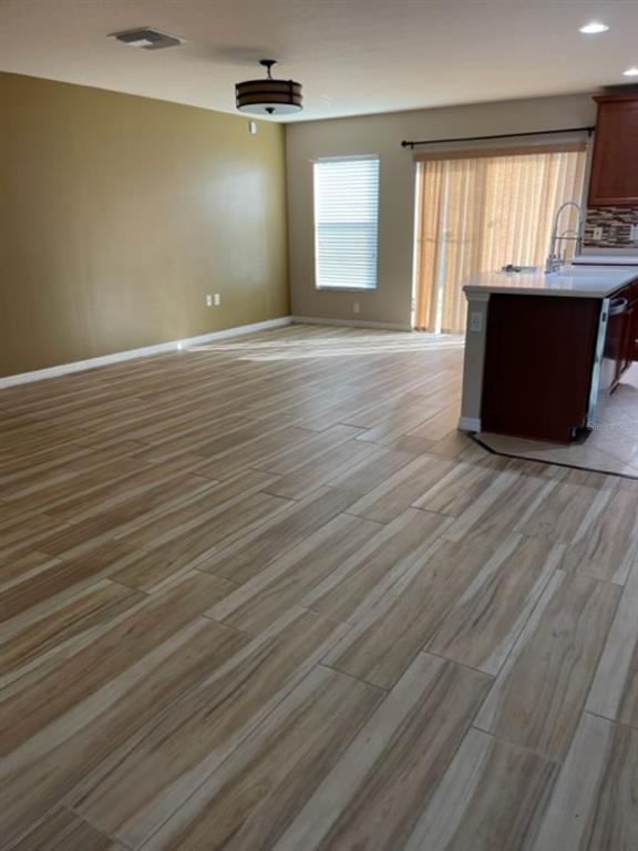 A room with wood-look tile flooring, a large mustard-colored wall, and an open kitchen island — 2950 WILLOWLEAF LANE, WESLEY CHAPEL, FL