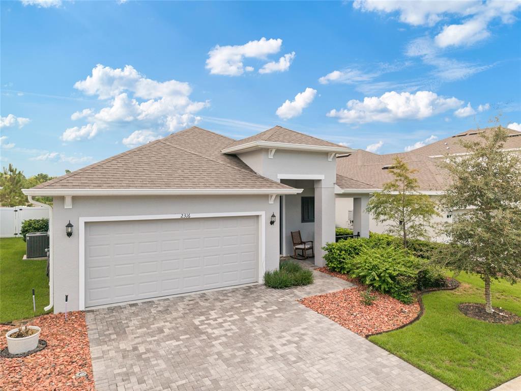 A single-story house with a gray garage, paved driveway, and a small front porch — 2316 SIRENA LANE, MOUNT DORA, FL