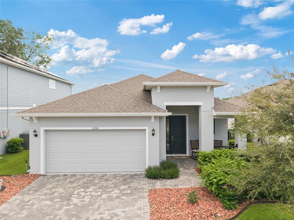 A single-story house with a gray stucco exterior, a two-car garage, and a paved driveway — 2316 SIRENA LANE, MOUNT DORA, FL