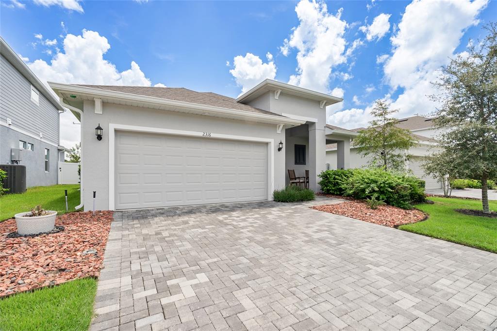 A single-story house with a gray stucco exterior, a two-car garage, and a paved driveway — 2316 SIRENA LANE, MOUNT DORA, FL