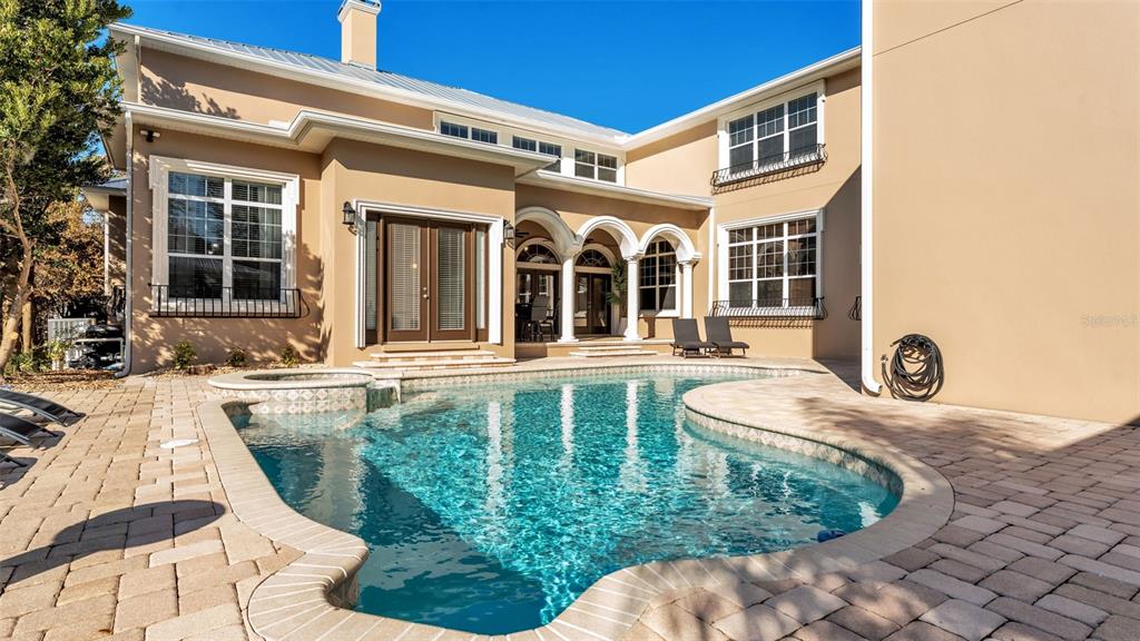 A tan two-story house features a swimming pool and patio in the backyard — 1665 BLUE HERON LANE, LAKELAND, FL