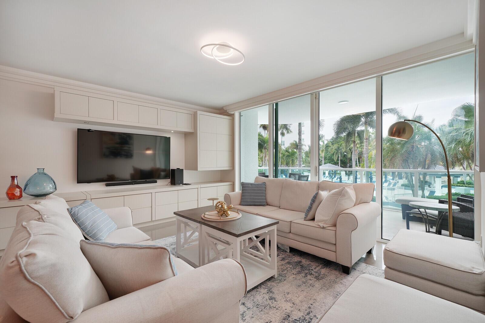 A living room with cream sofas, a coffee table, built-in cabinetry, and a balcony view — 550 SE Mizner Boulevard # B209, Boca Raton FL 33432, BOCA RATON, FL