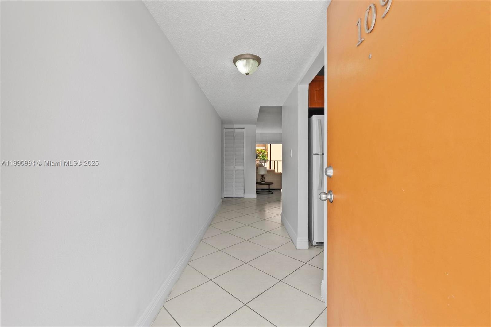 A tiled entryway leads to a hallway with a closet and a view of a balcony — 1800 W 54th St # 109, Hialeah FL 33012, HIALEAH, FL