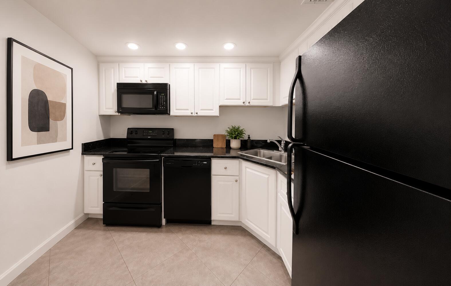 A kitchen features white cabinets, black appliances, dark countertops, and light-colored tile flooring — 3740 Inverrary Drive # 3g, Lauderhill FL 33319, LAUDERHILL, FL