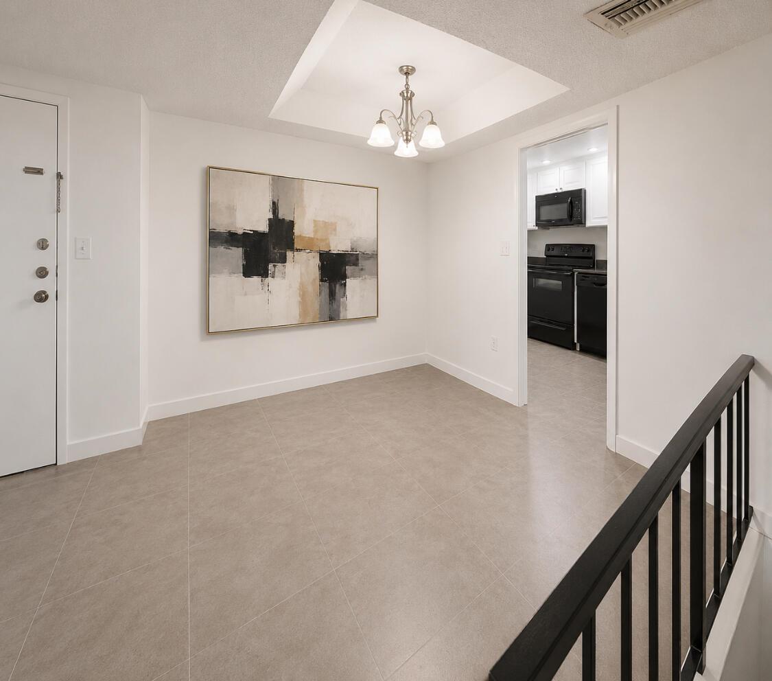 An empty dining area features light tile flooring, a central chandelier, and abstract wall art — 3740 Inverrary Drive # 3g, Lauderhill FL 33319, LAUDERHILL, FL