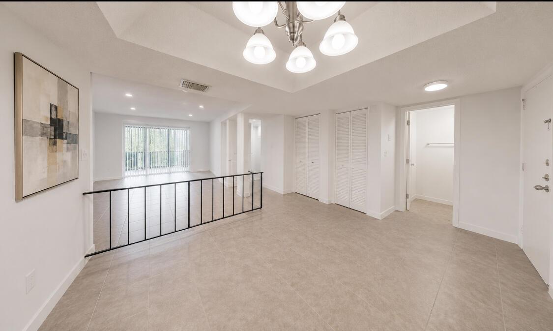 An open-concept room features light tile flooring, a black metal railing, and a tray ceiling — 3740 Inverrary Drive # 3g, Lauderhill FL 33319, LAUDERHILL, FL