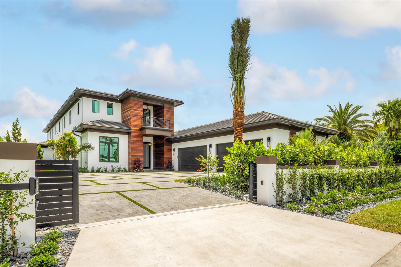 A modern two-story house features white stucco, wood siding, a paved driveway, and palm trees — 1708 N Lakeside Drive, FL 33460, FL