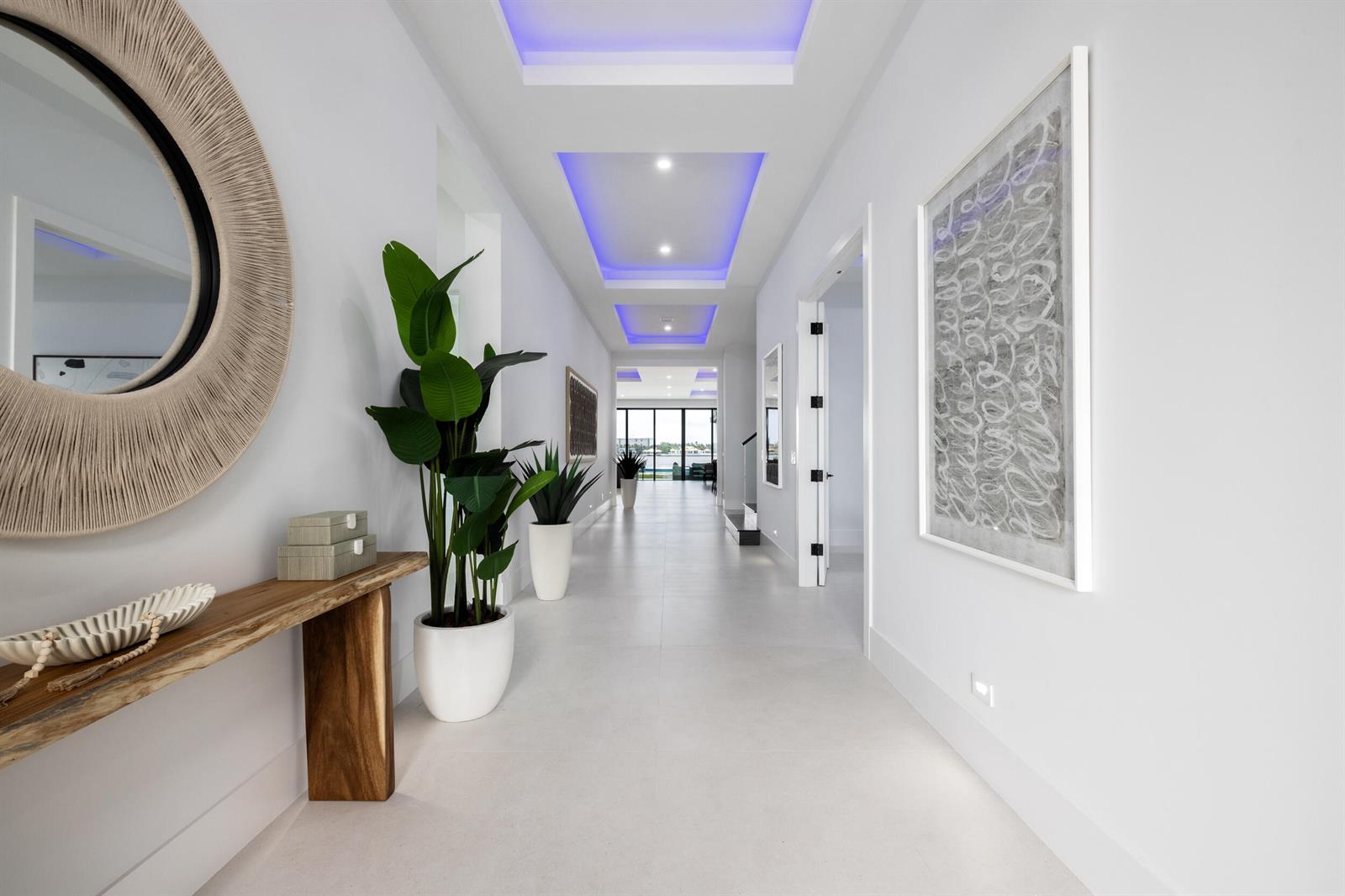A bright, modern hallway features white tile floors, recessed blue lighting, and a wooden console — 1708 N Lakeside Drive, FL 33460, FL