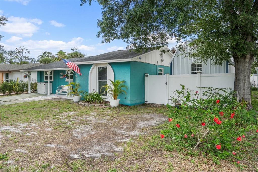 A teal single-story house with a white arched window and a white fence — 7906 WOODVINE CIRCLE, TAMPA, FL