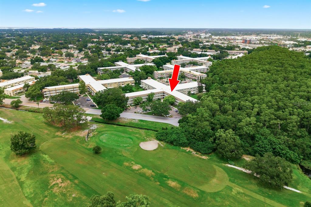An aerial view shows a multi-story apartment complex situated next to a golf course — 2440 WORLD PARKWAY BOULEVARD UNIT 34, CLEARWATER, FL