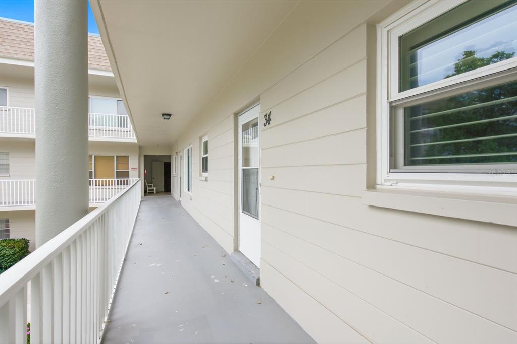 An exterior walkway with a white railing leads to a door marked with number 34 — 2440 WORLD PARKWAY BOULEVARD UNIT 34, CLEARWATER, FL